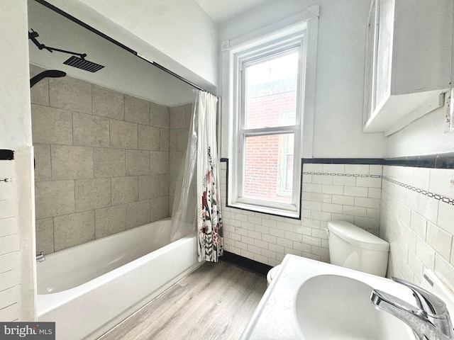 bathroom with wood finished floors, a sink, toilet, and shower / tub combo