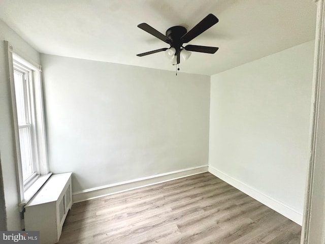 empty room featuring wood finished floors, a ceiling fan, and baseboards