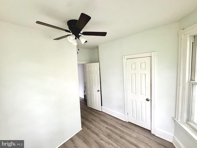 unfurnished bedroom featuring wood finished floors, baseboards, and ceiling fan