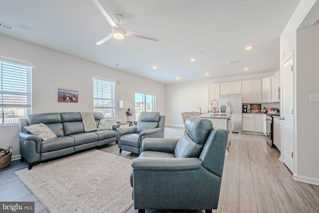 living room with light wood-type flooring and ceiling fan