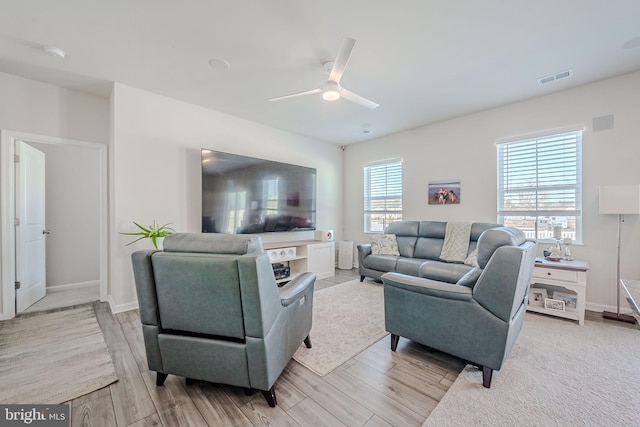 living room featuring ceiling fan, plenty of natural light, and light wood-type flooring