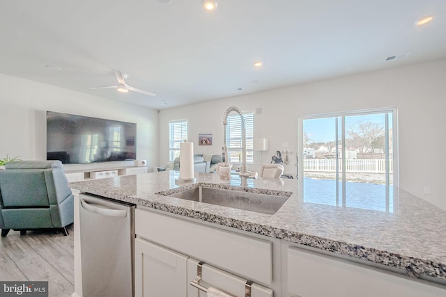 kitchen featuring white cabinets, a healthy amount of sunlight, light hardwood / wood-style floors, sink, and stainless steel dishwasher