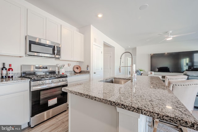 kitchen with sink, a breakfast bar area, white cabinetry, and stainless steel appliances