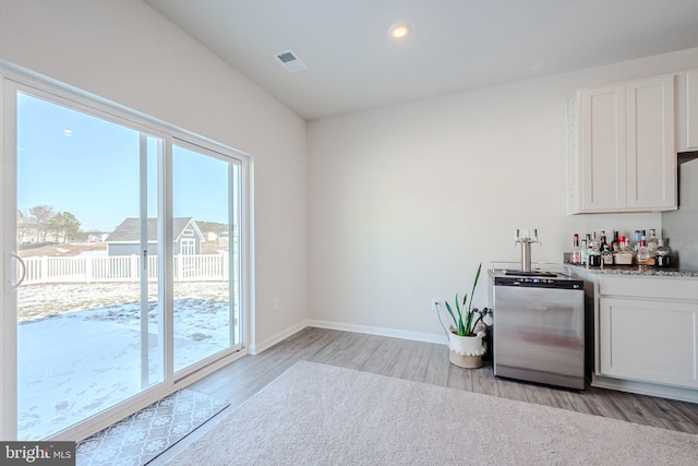 kitchen with sink, white cabinetry, dishwashing machine, and light hardwood / wood-style flooring