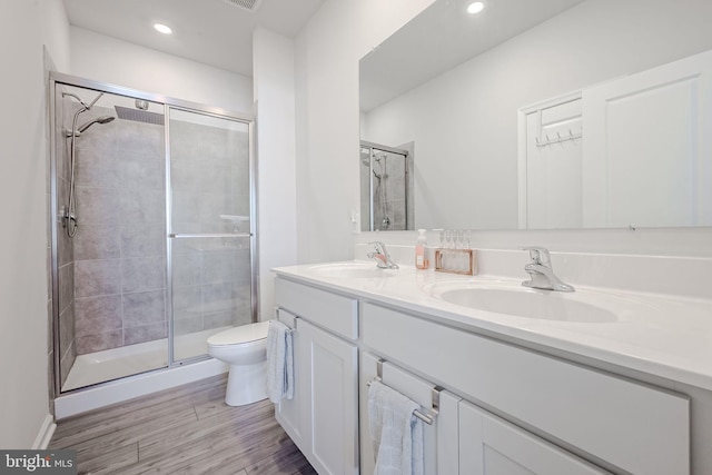 bathroom with wood-type flooring, toilet, a shower with door, and vanity