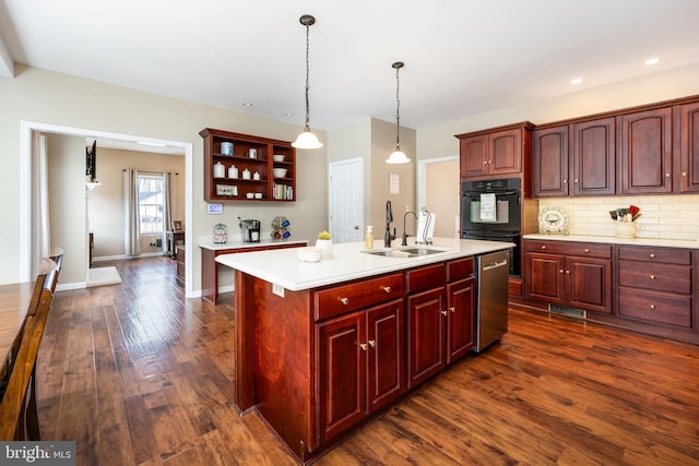 kitchen featuring sink, a kitchen island with sink, double oven, decorative light fixtures, and stainless steel dishwasher