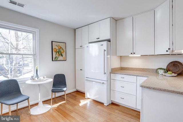 kitchen featuring visible vents, a healthy amount of sunlight, white cabinetry, and freestanding refrigerator