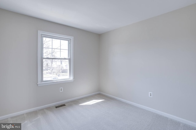 empty room featuring visible vents, light carpet, and baseboards