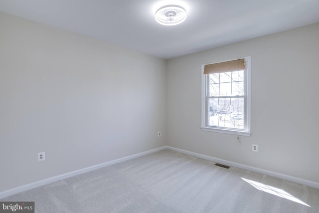 spare room featuring visible vents, light carpet, and baseboards