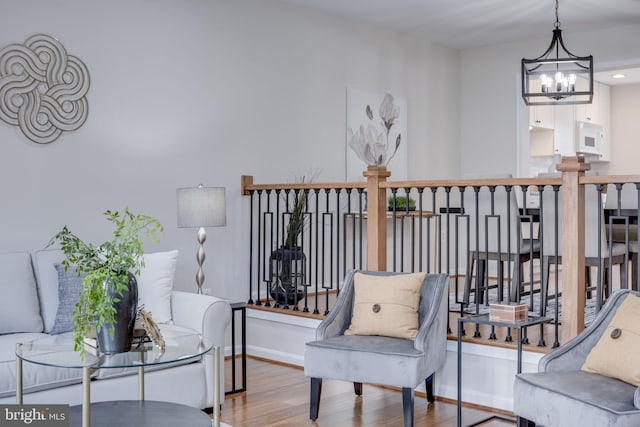 living area featuring baseboards, a notable chandelier, and wood finished floors