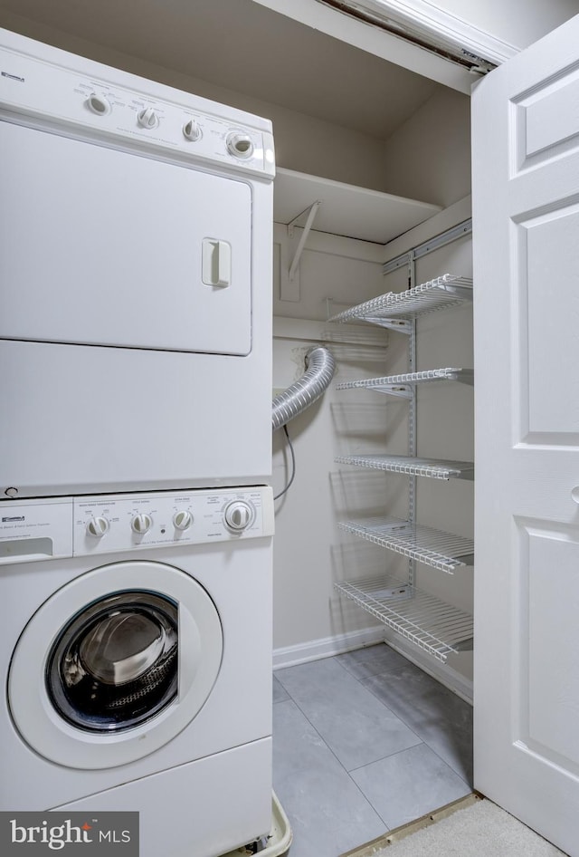 laundry room featuring tile patterned floors, laundry area, and stacked washing maching and dryer