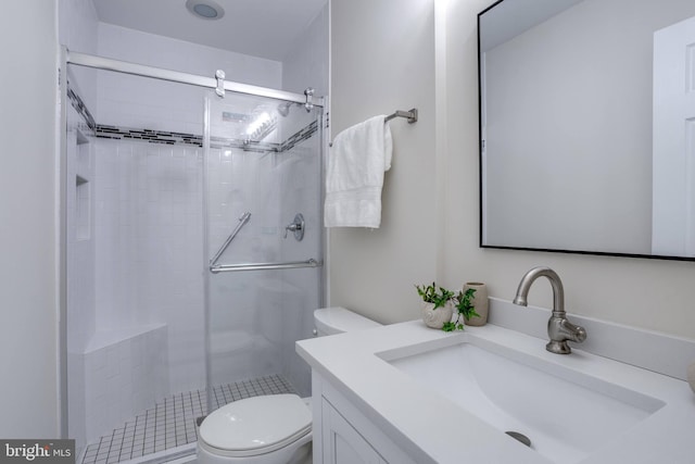 bathroom featuring a shower stall, toilet, and vanity