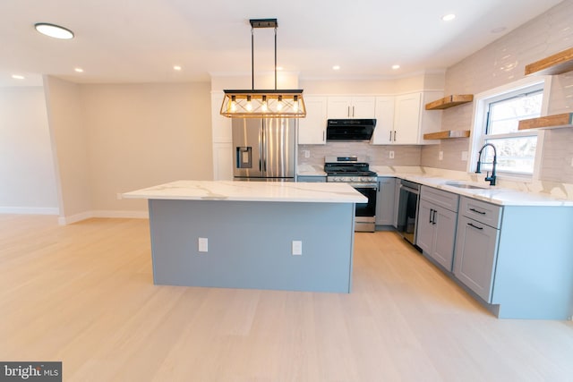 kitchen with pendant lighting, sink, white cabinetry, stainless steel appliances, and a kitchen island