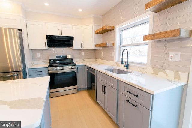 kitchen featuring tasteful backsplash, white cabinetry, sink, light stone counters, and stainless steel appliances