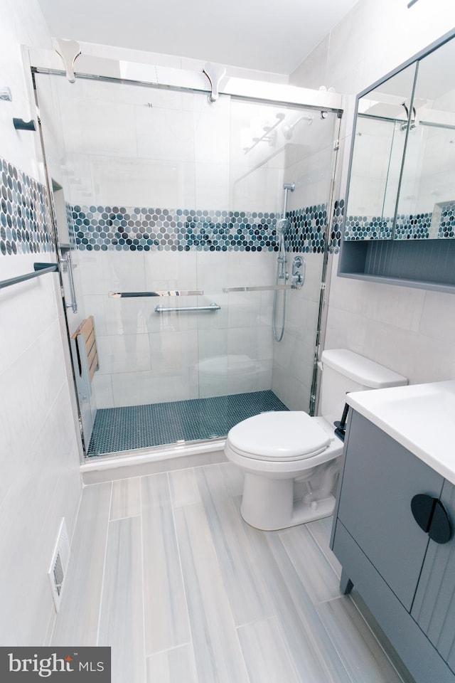 bathroom with vanity, toilet, and a shower with shower door