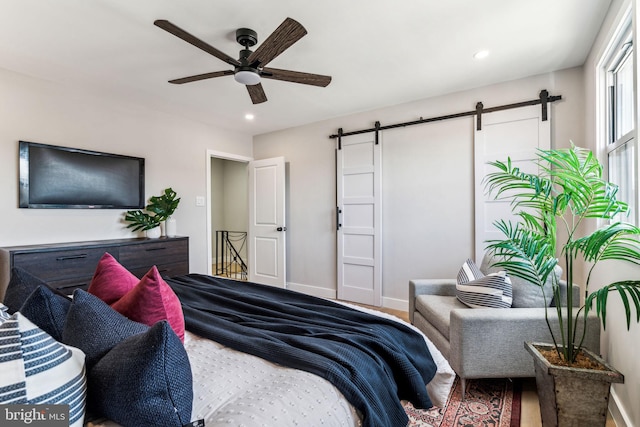 bedroom featuring ceiling fan and a barn door