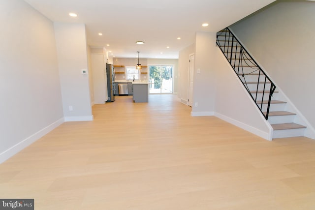 unfurnished living room with sink and light hardwood / wood-style flooring