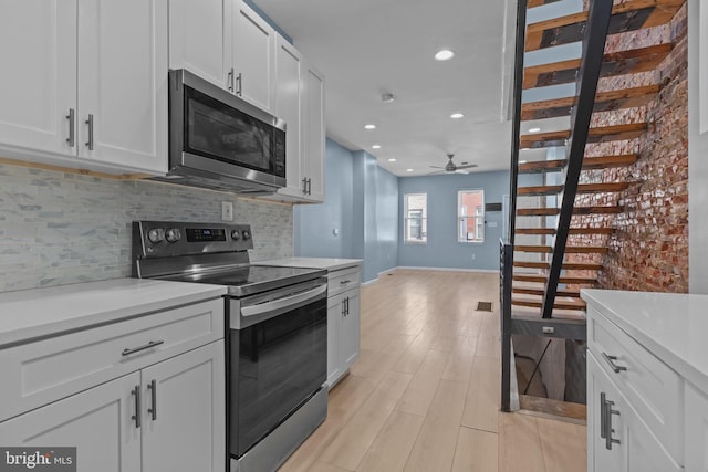 kitchen with ceiling fan, appliances with stainless steel finishes, light wood-type flooring, white cabinetry, and decorative backsplash