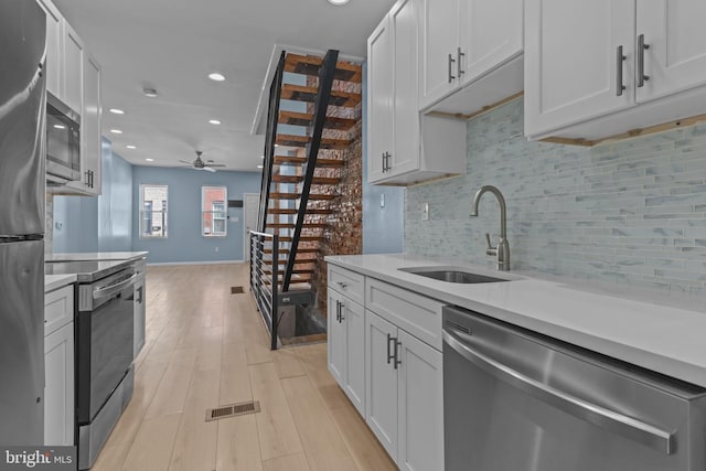 kitchen featuring sink, backsplash, white cabinetry, and stainless steel appliances