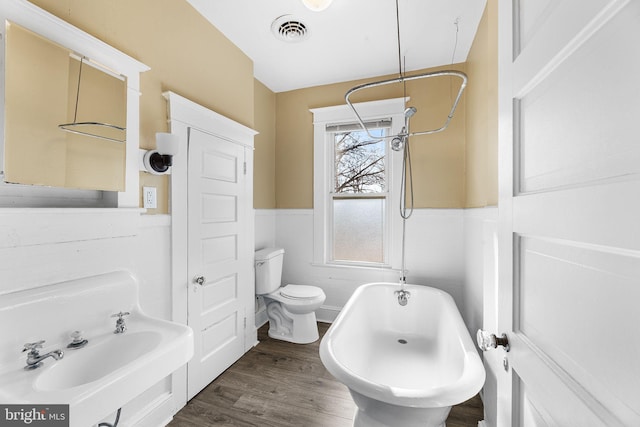 bathroom featuring toilet, hardwood / wood-style floors, and a tub