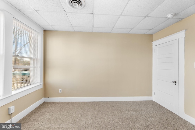 spare room featuring carpet flooring and a drop ceiling