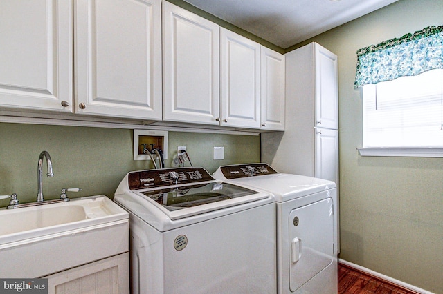 clothes washing area with a sink, baseboards, washing machine and dryer, cabinet space, and dark wood-style flooring