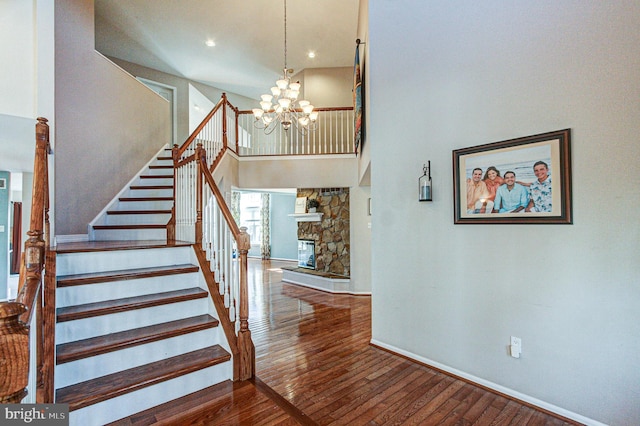 stairway featuring hardwood / wood-style floors, a fireplace, baseboards, and a chandelier