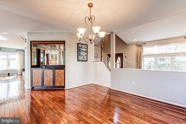 empty room featuring a wealth of natural light, stairway, and wood-type flooring