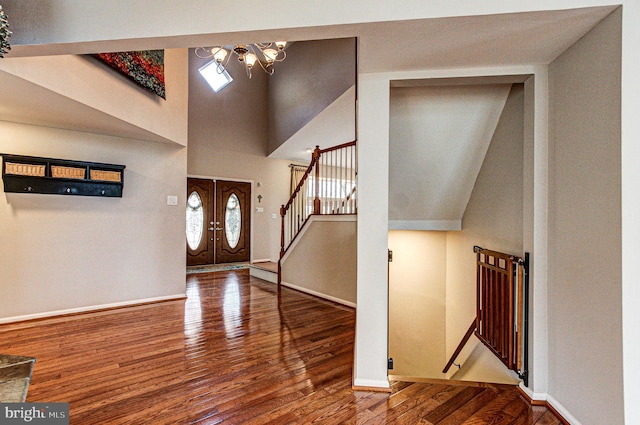 foyer featuring hardwood / wood-style floors, baseboards, a high ceiling, stairs, and a chandelier