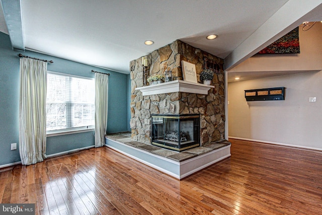 unfurnished living room with baseboards, a fireplace, and hardwood / wood-style flooring