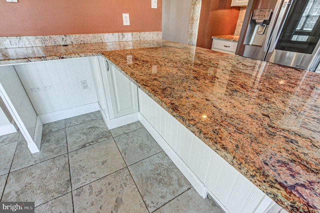 kitchen featuring white cabinetry, light stone countertops, and stainless steel fridge