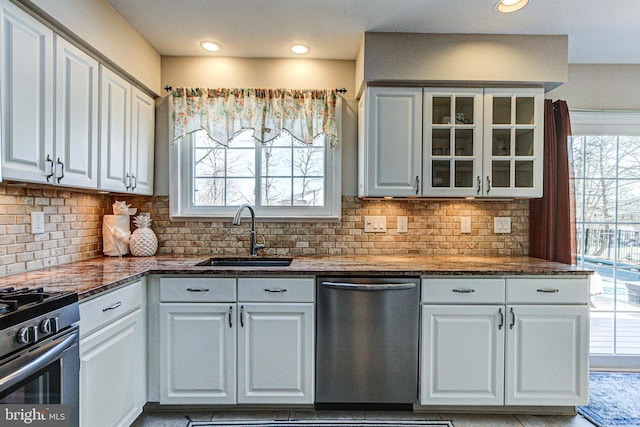 kitchen with a sink, glass insert cabinets, appliances with stainless steel finishes, and a healthy amount of sunlight