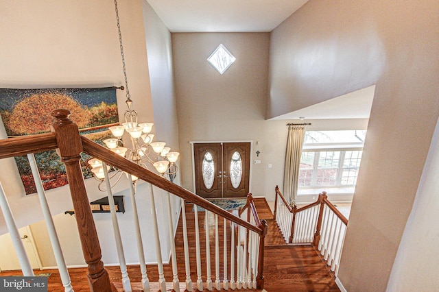 stairway featuring plenty of natural light, french doors, a high ceiling, and wood finished floors