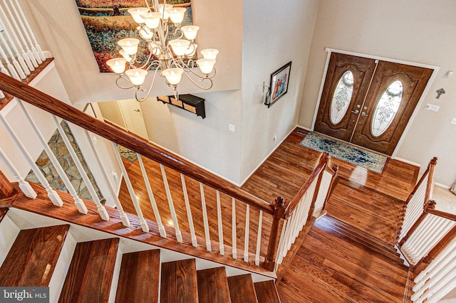 entryway featuring a notable chandelier, wood finished floors, and stairs