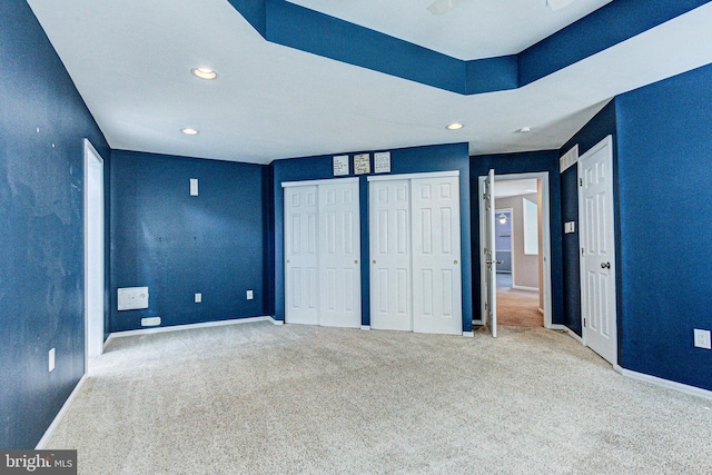 unfurnished bedroom featuring recessed lighting, carpet, multiple closets, and baseboards