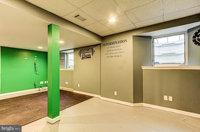 below grade area with visible vents, a paneled ceiling, and baseboards