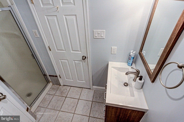 bathroom with baseboards, a shower stall, and vanity