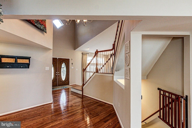 foyer entrance with stairway, baseboards, an inviting chandelier, a high ceiling, and wood-type flooring