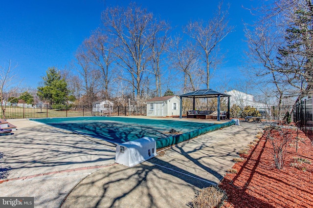 view of swimming pool featuring an outbuilding, fence, a fenced in pool, a gazebo, and a patio area