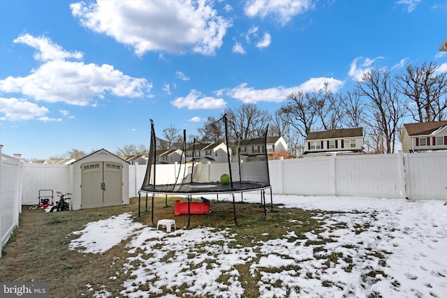 yard layered in snow with a shed and a trampoline