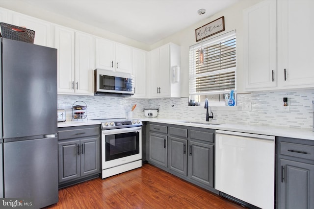 kitchen with stainless steel appliances, gray cabinets, sink, and white cabinets