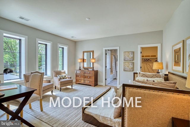 bedroom featuring a closet, light hardwood / wood-style floors, connected bathroom, and a walk in closet