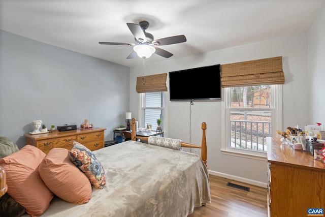 bedroom with ceiling fan, multiple windows, and light wood-type flooring