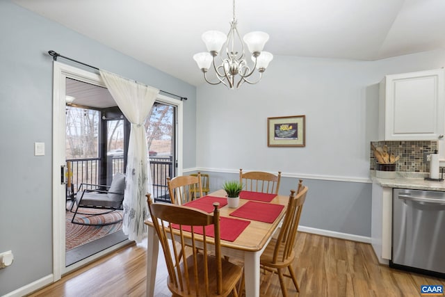 dining area with a notable chandelier, vaulted ceiling, and light hardwood / wood-style floors