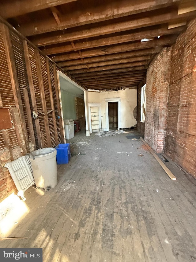 misc room featuring hardwood / wood-style flooring and brick wall