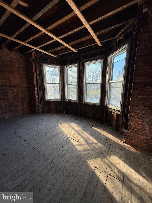 miscellaneous room featuring a healthy amount of sunlight, hardwood / wood-style flooring, and brick wall