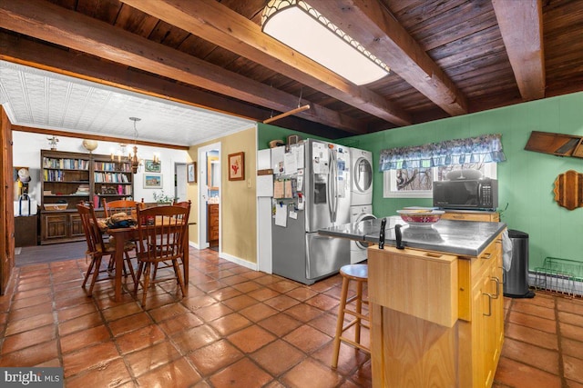 kitchen with beamed ceiling, a kitchen breakfast bar, stainless steel counters, stacked washer / drying machine, and stainless steel refrigerator with ice dispenser