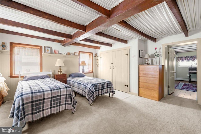 bedroom featuring beam ceiling, light carpet, and multiple windows