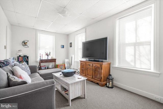 living room with a paneled ceiling and carpet