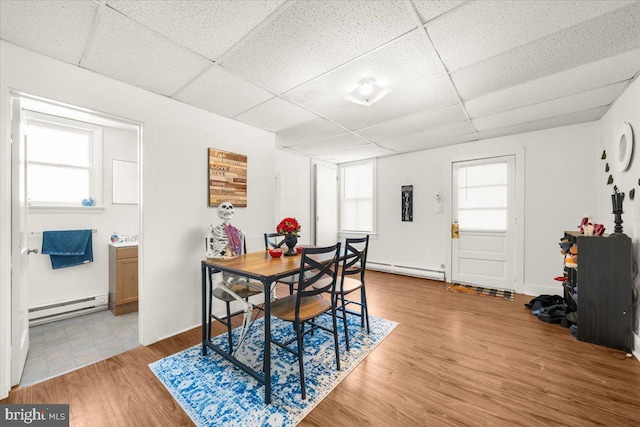 dining area with hardwood / wood-style flooring, a baseboard radiator, and a paneled ceiling